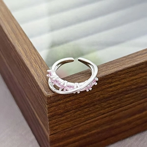 Detail of silver adjustable ring with pink marquise zircon stones on a wooden jewelry box