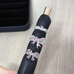 Detailed macro of three silver bow rings with pink zircon stones on a display stand