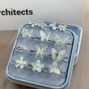 Detail von Emaille-Schmetterlings- und Blumenringen in einer blauen Samtbox