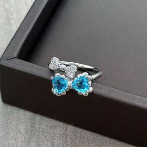 Detail shot of a silver bow ring featuring blue heart-shaped gems and micro-set zircons