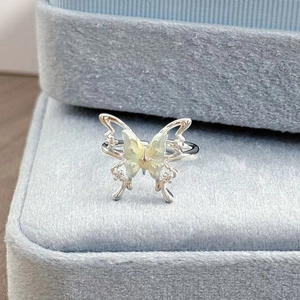 Detailaufnahme eines silbernen Schmetterlingsrings mit grünem Emaille auf blauem Samt