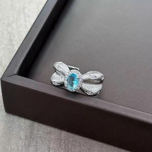 Close-up of bow ring with blue gemstone and white pavé zircon stones on stone background
