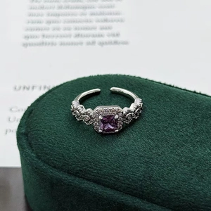 Detailed macro view of silver-tone ring with square purple zircon and engraved side band