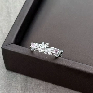 Detail of silver bow ring with pink zircon accents and rabbit motif on marble base