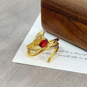 Close-up of golden snake ring featuring oval red zircon and sparkling crystal eyes