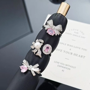 Detail of four pink zircon bow rings with pearls and heart stones on black leather