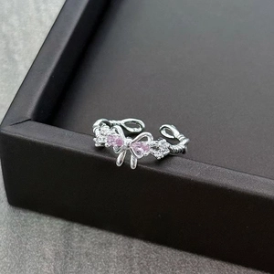 Macro detail of silver bow ring featuring a pink teardrop stone and shimmering accents