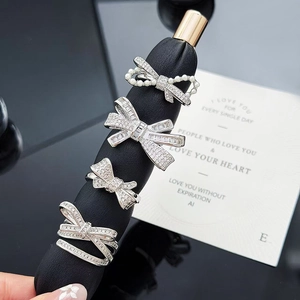 Bow tie silver rings with zircon stones and pearls on a professional display stand