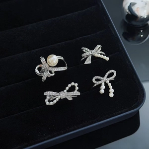 Detailed view of silver bow jewelry set with zircon and pearls in a black velvet box