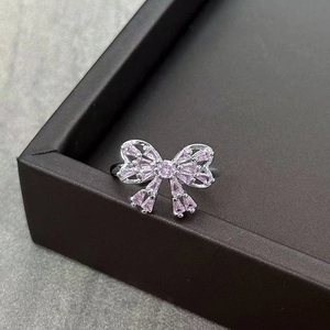 Detail view of pink gemstone bow ring with silver open band on black jewelry stand