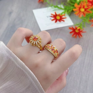 Detail of vintage style gold rings featuring orange zircon and flower design on fingers