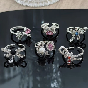 Set of silver bow rings with colorful zircon stones and pearls on a black mirror