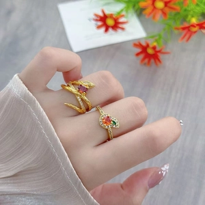 Detail of vintage gold open rings with orange zircon and floral accents on fingers