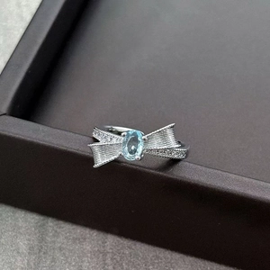 Detailed macro view of silver bow ring featuring light blue gemstone and pavé zircon stones