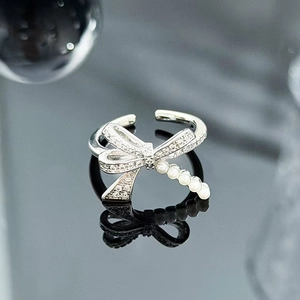 Detail of silver bow ring featuring sparkling zircons and delicate white pearls