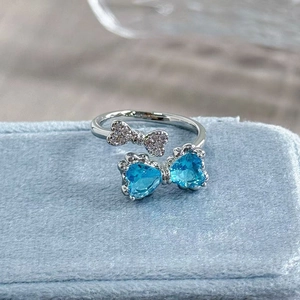 Close-up of butterfly ring with blue heart gemstones and pavé zircon on velvet box