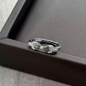 Detail of silver open ring with heart green gemstones and white zircon accents
