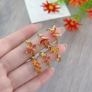 Macro detail of gold butterfly rings with orange zircons and floral accents