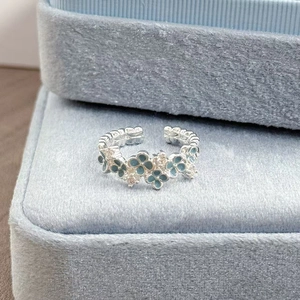 Detailansicht Emaille-Blumenring mit Zirkonia auf blauem Samt-Schmuckkästchen