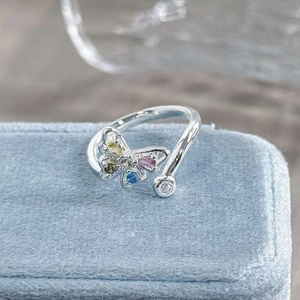 Detailed close-up of a butterfly ring with colorful zircons on light blue velvet