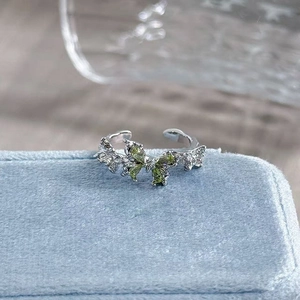 Macro shot of butterfly open ring with olive green gemstones and silver pavé details