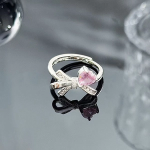 Detail of silver bow ring with shimmering heart pink stone and zircon inlay