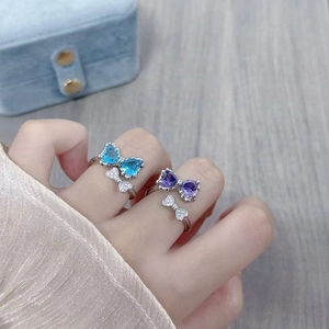 Detailed view of silver bow rings with blue and purple heart-shaped cubic zirconia