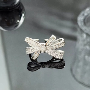 Detailed view of silver bow ring featuring baguette and round zirconia on a dark surface