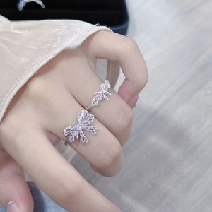 Close-up of dual silver bow rings featuring pink and clear crystals on fingers