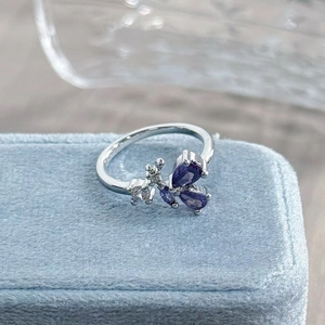 Macro shot of silver butterfly ring with purple pear-cut zircons on a blue velvet box