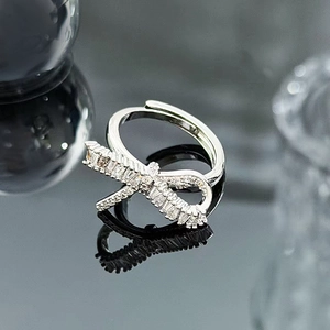 Close-up of a silver bow ring with sparkling zircons on a reflective dark surface