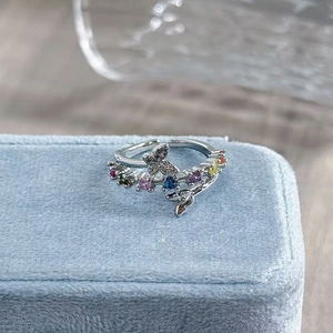 Close-up of silver butterfly ring with multi-colored gemstones and pavé-set crystals
