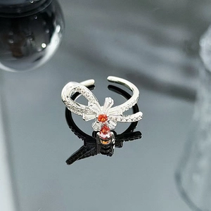 Detailed macro of a silver bow ring with orange gems and white cubic zirconia accents
