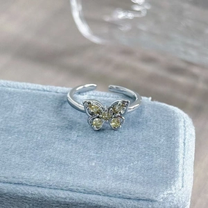 Detail of silver butterfly ring with pale yellow zircon stones on blue velvet box