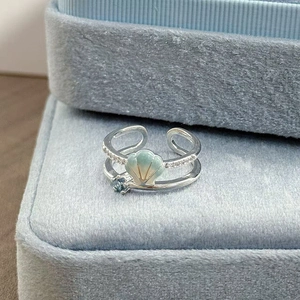 Makro-Detail von silbernem Ring mit Muschel und blauem Zirkon auf Samt