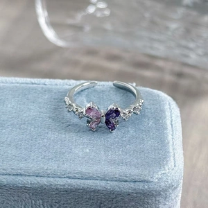 Macro shot of silver butterfly ring with purple gemstones on light blue jewelry box