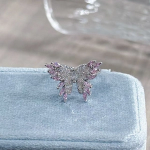 Close-up of luxury butterfly ring with pink and white cubic zirconia on blue velvet