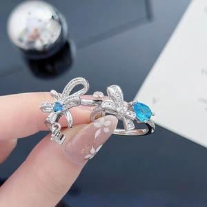 Detailed macro view of silver bow rings featuring blue round and pear-shaped zircons