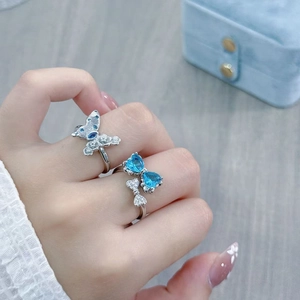 Close-up of butterfly and bow rings featuring blue zircons and white pave diamonds