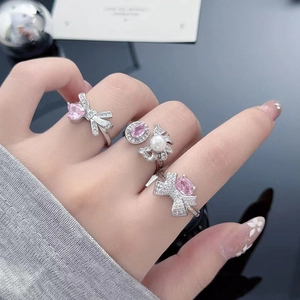 Detail of silver bow rings with pink zircon gems and pearls worn by a female model