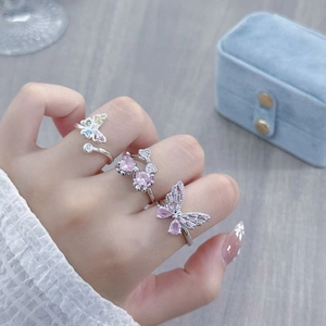 Detailed close-up of three sparkling butterfly rings with pink zircon on hand