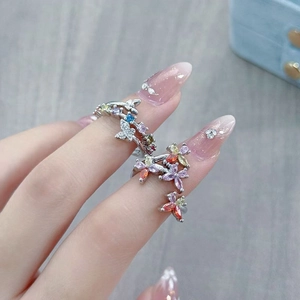 Close-up of butterfly and flower zircon rings on finger with colorful gemstones