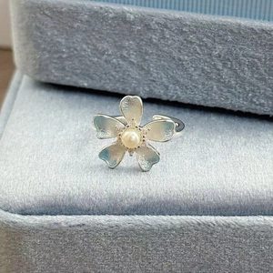 Makroaufnahme Silberring in Blumenform mit blauen Blütenblättern und Perle in der Mitte