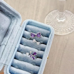 Close-up of purple heart-shaped gemstone butterfly rings in a velvet jewelry box