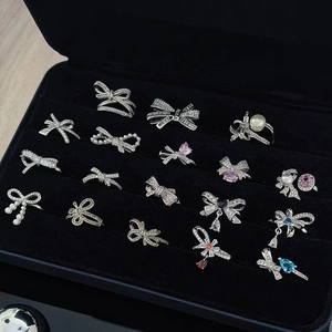 Sparkling silver bow rings with colorful gems and pearls on black velvet display
