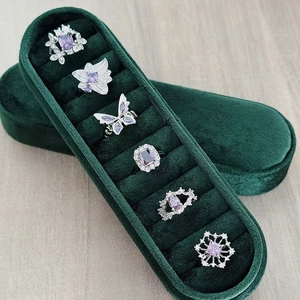 Detail view of silver rings set with purple zircons and butterfly design in a green box