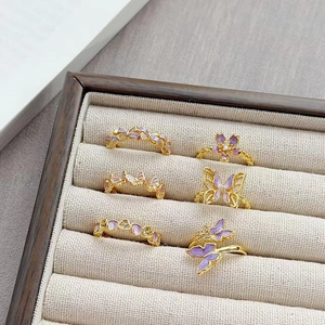 Detail van vergulde ringen met paarse emaille vlinder en vintage bloemmotieven