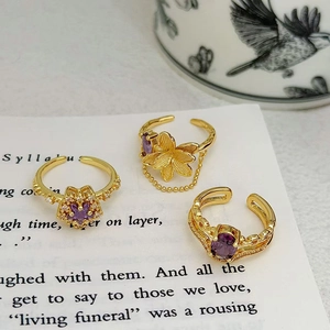 Detaillierte Nahaufnahme von drei vergoldeten Vintage-Ringen mit lila Zirkonia und Blumen