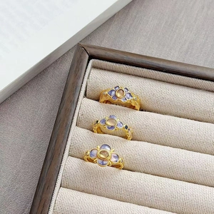Detailweergave van vintage gouden ringen met paarse emaille bloemen in houten tray