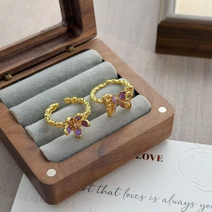 Gedetailleerd beeld van vintage gouden ringen met paarse emaille bloem en vlinder